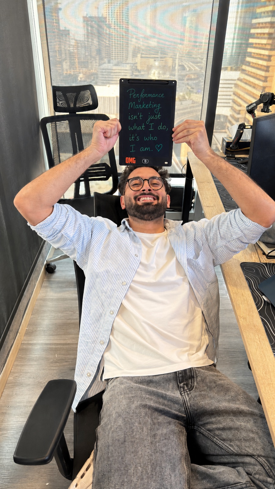 Abhishek Thakral in his Dubai office, holding a tablet that reads: Performance marketing isn't just what I do, it's who I am.